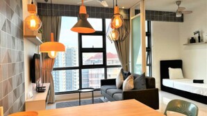 A modern hotel room with a dining area, a sofa, a bed, and large windows offering a city view. - The Robertson Residences Free Gym & Pool (Kuala Lumpur)