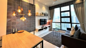 A modern living room with a sofa, a dining table, and a TV. - The Robertson Residences Free Gym & Pool (Kuala Lumpur)