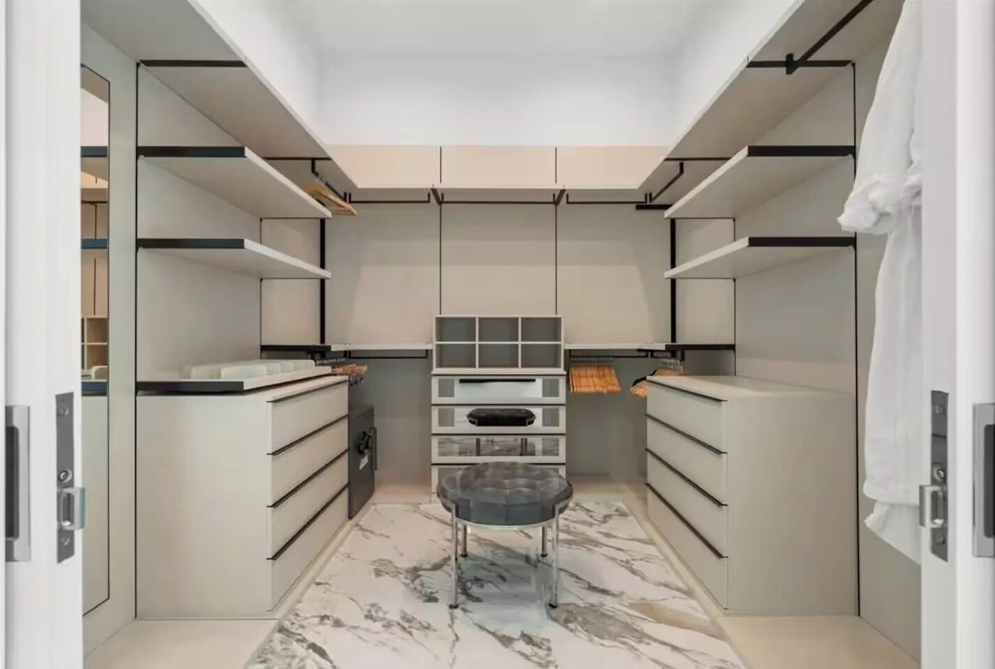 Un dressing moderne, doté d’étagères intégrées, de tiroirs et d’un espace de repos central.