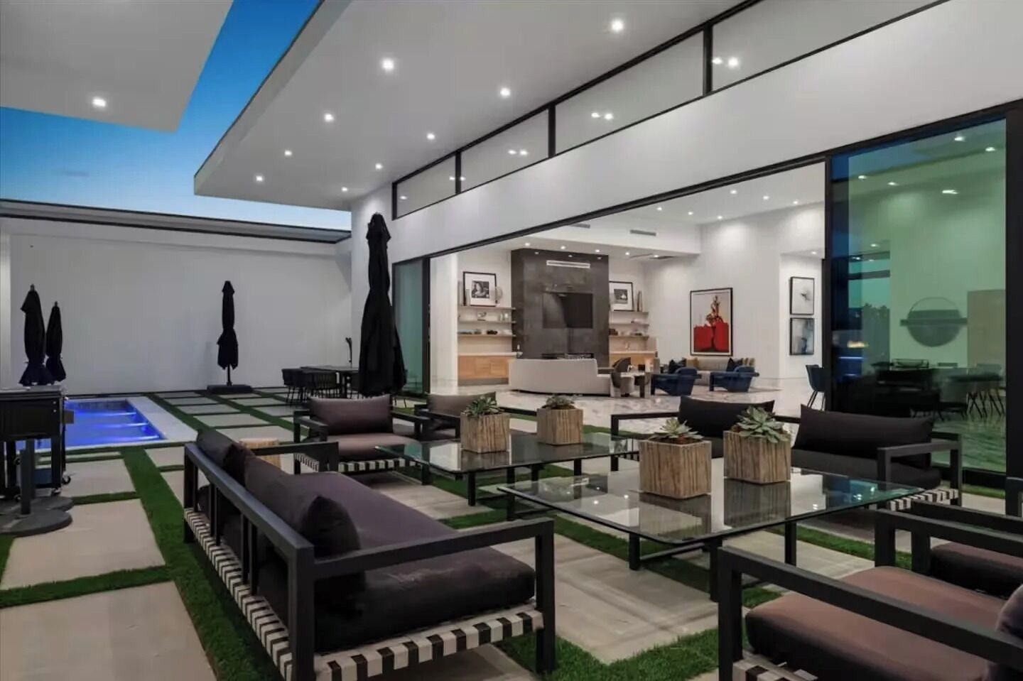 Una sala de estar moderna con una mesa de centro de vidrio, sofás y una zona de piscina.