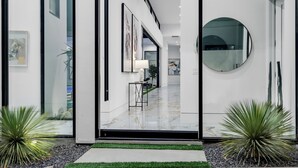A modern hallway with glass doors, a marble floor, and a round mirror on the wall. - Sleeps 17 | Private Pool + Pickleball Court + Fire Pit • Near La Quinta | Bravo (Indio)