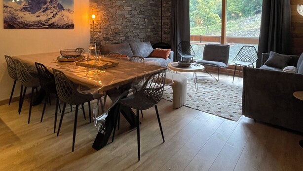 A modern living space with a dining area, stone wall, and large windows. - New Le Corbier for 10 p. Renovated top-of-the-range 4bed/2bath/2wc/slope frontage (Villarembert)