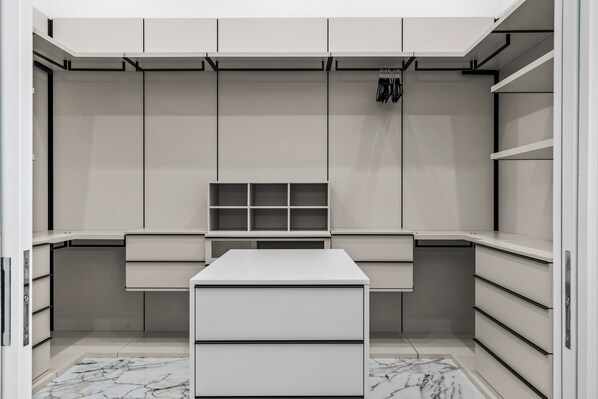 A modern, minimalist closet with built-in shelves and a central storage unit.