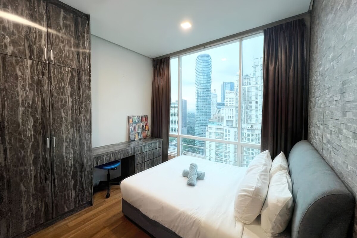Ein modernes Hotelzimmer mit einem großen Bett, einem Schreibtisch und Blick auf eine Stadtlandschaft.