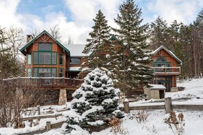 A large, multi-story lodge with a prominent balcony and a snow-covered landscape.