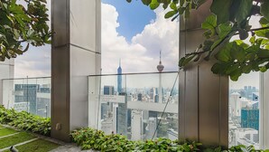 Een modern gebouw met een glazen balkon met uitzicht op een stadsgezicht, inclusief een opvallende toren.