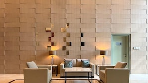 A modern lobby with a geometric wall design, two sofas, a coffee table, and two lamps. - The Lofts Central, Burj khalifa View (Dubai)