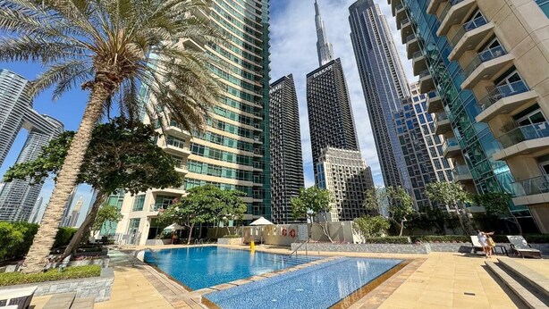 A modern urban setting with high-rise buildings, a swimming pool, and palm trees. - The Lofts Central, Burj khalifa View (Dubai)