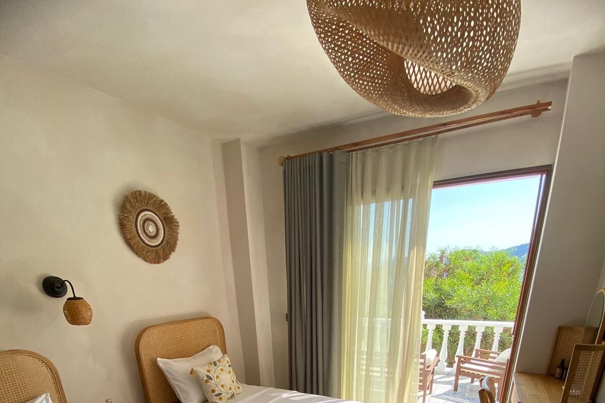 Habitación de hotel con dos camas, un balcón y vista a zonas verdes.