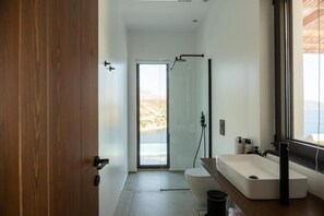 A modern bathroom with a large window, a shower, and a sink.