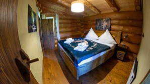 Un dormitorio tipo cabaña de madera con una cama, paredes de madera, una lámpara en el techo y un cuadro.
