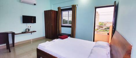 Ein Schlafzimmer mit Bett, Fernseher, Kleiderschrank und einem Fenster mit Vorhängen.