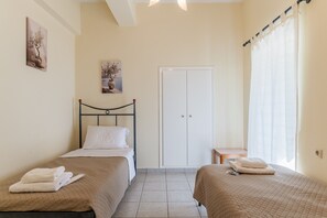 A bedroom with two beds, a wardrobe, a small table, and artwork on the walls.