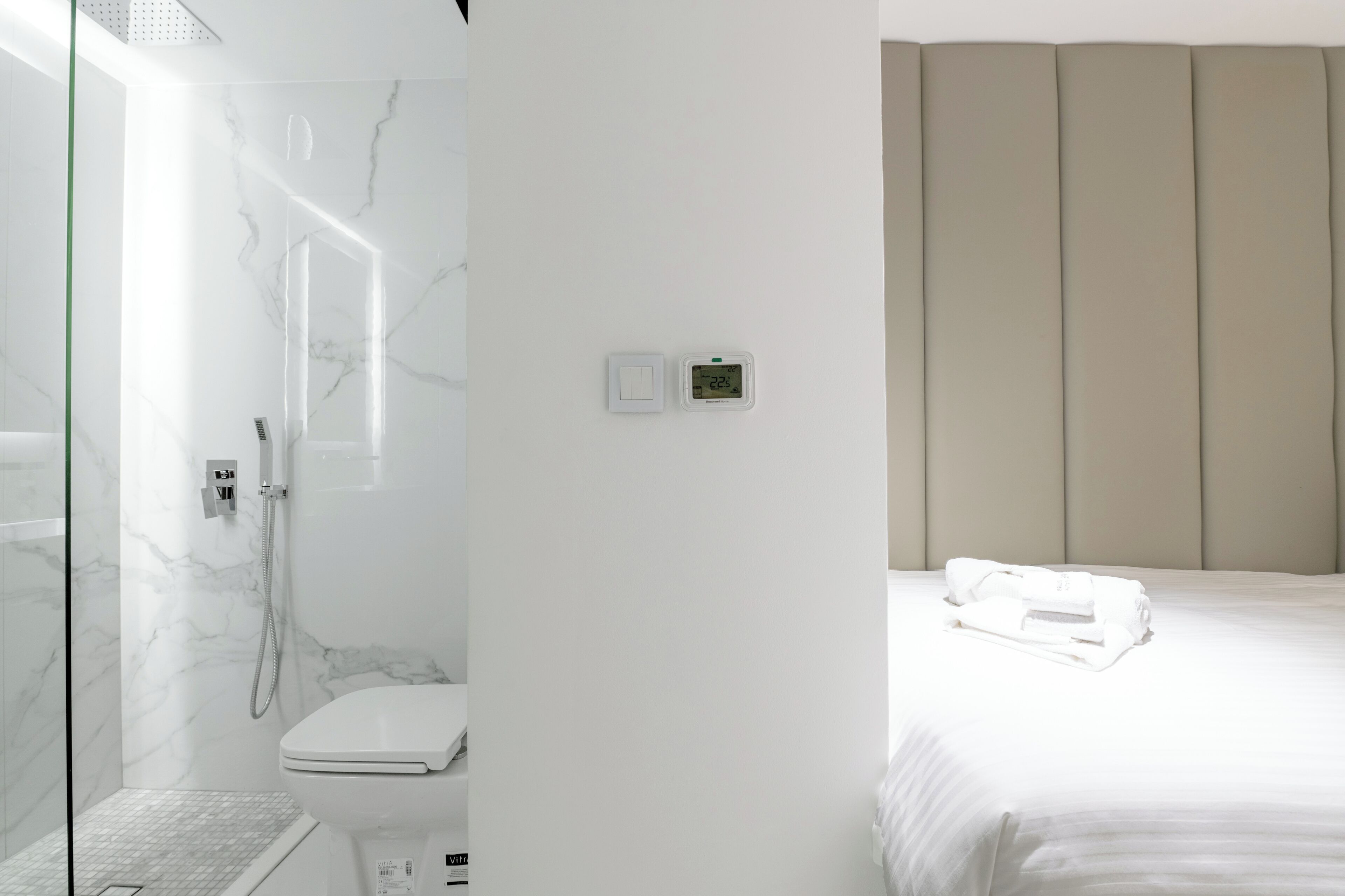 Een moderne badkamer met een douche met glazen wand, een toilet en een bedieningspaneel.