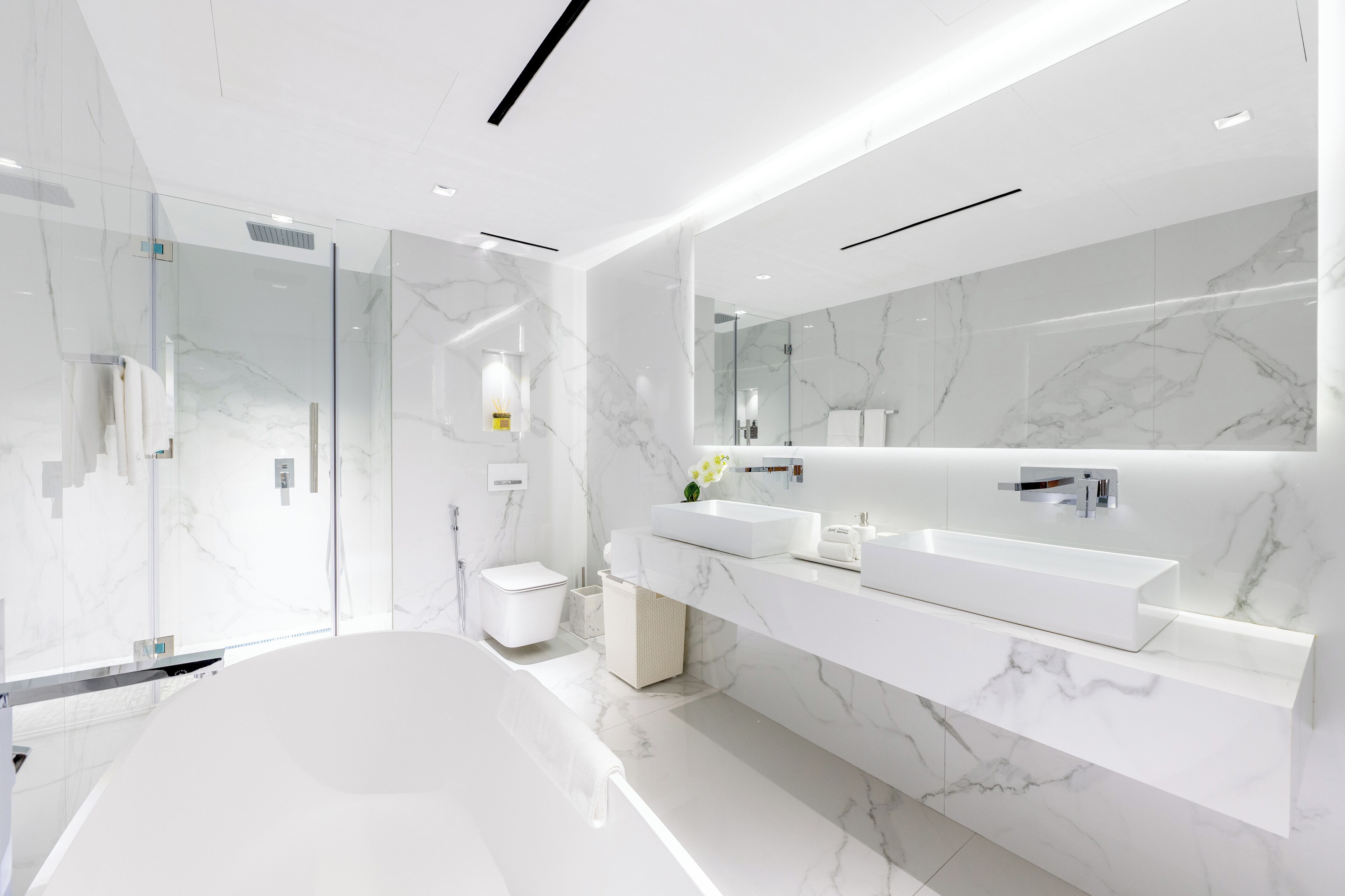 Un baño moderno con una bañera grande, un box de ducha de vidrio y un salpicadero de mármol.
