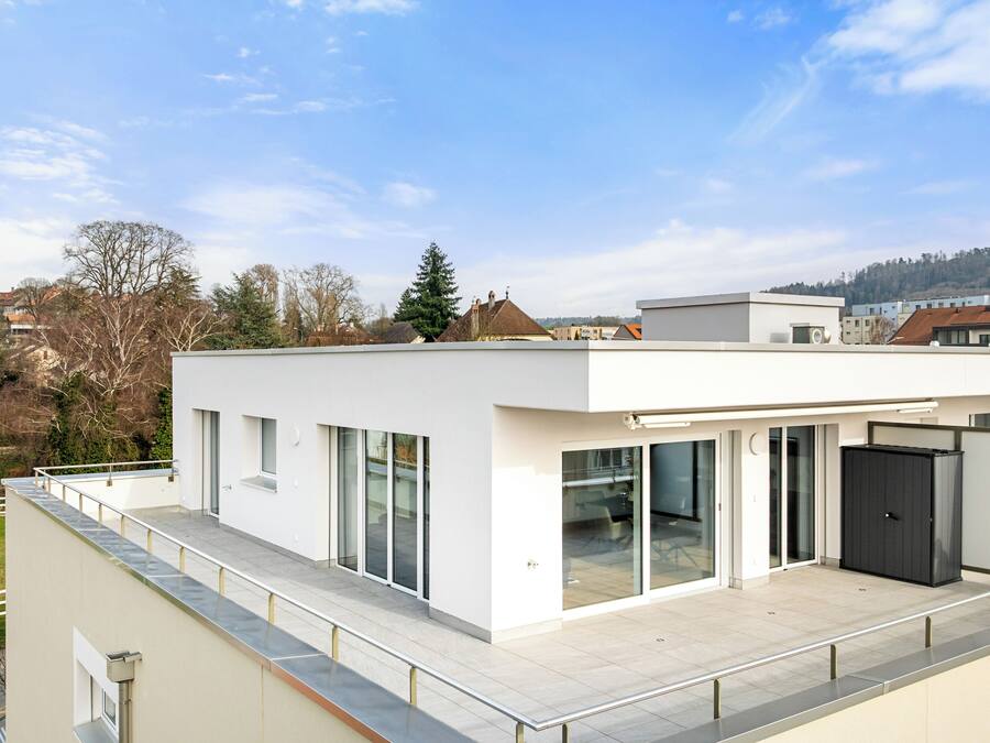 A modern building with large windows, a flat roof, and a balcony.