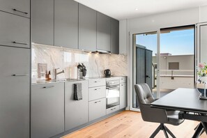 Une cuisine moderne avec des meubles gris, un pare-feu en marbre et un coin repas comprenant une table et des chaises.