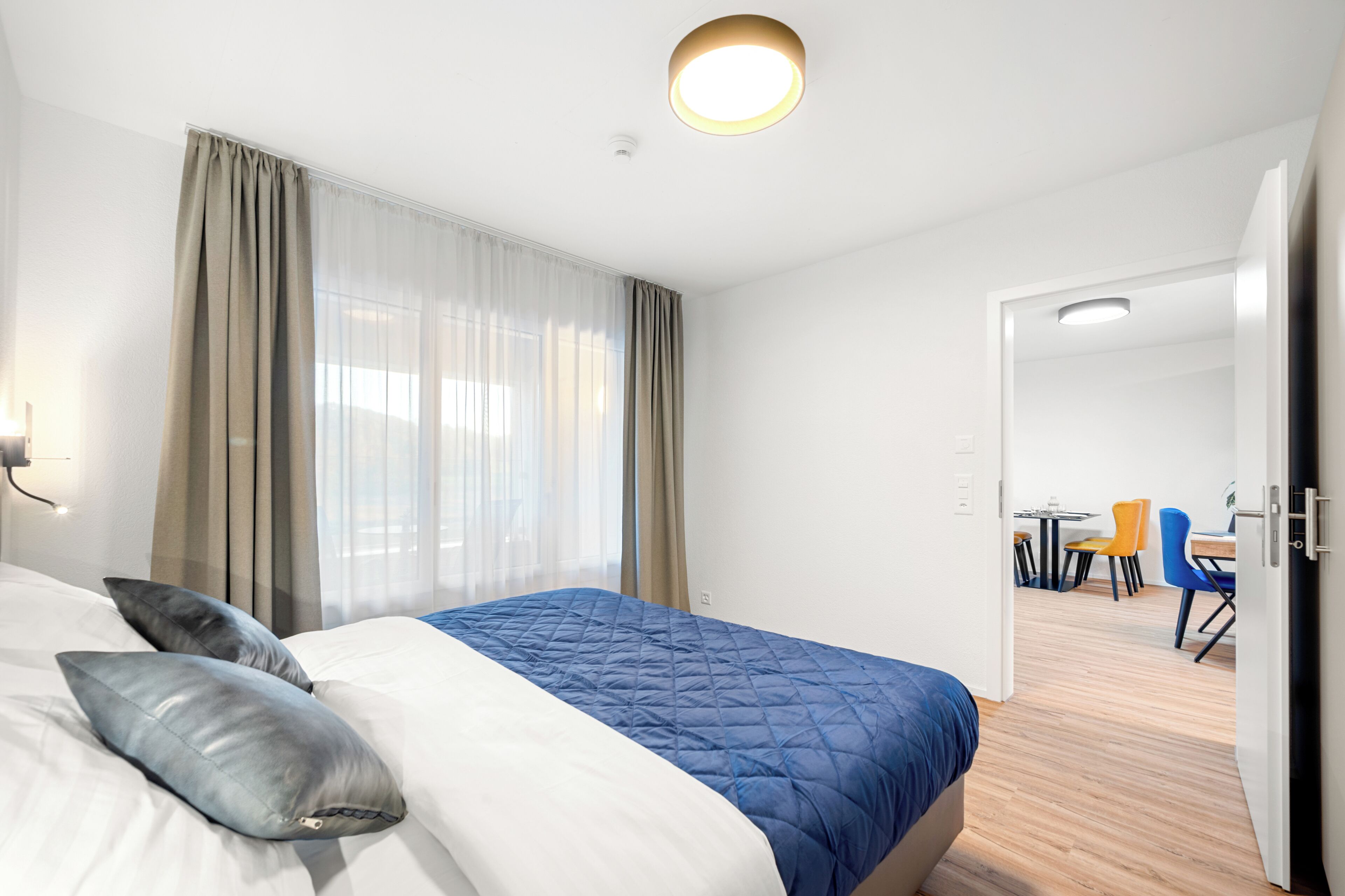 Habitación de hotel con cama, cortinas, escritorio y sillas.