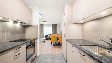 Una cocina moderna con horno empotrado, un lavamanos de acero inoxidable y un comedor con sillas amarillas.