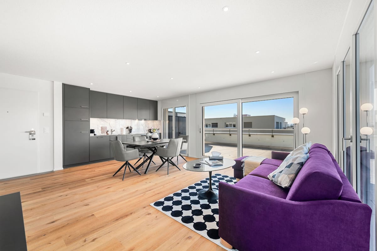 Un apartamento moderno con cocina, comedor y sala de estar con un sofá morado.