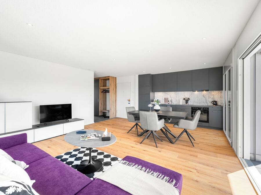 A modern living space with a sofa, dining table, and kitchen area.