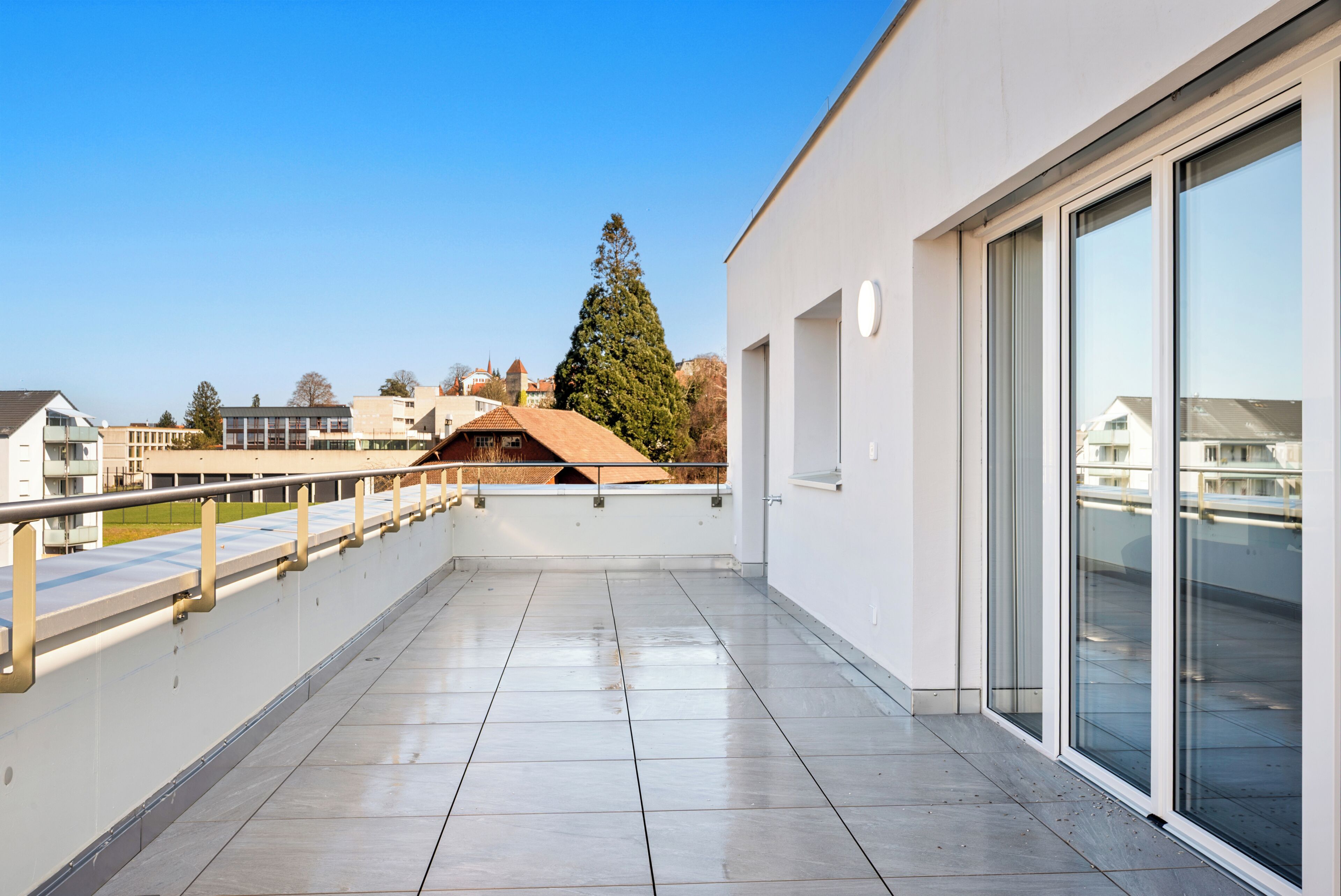 Un edificio moderno con balcón, ventanas amplias y una vista despejada del entorno.