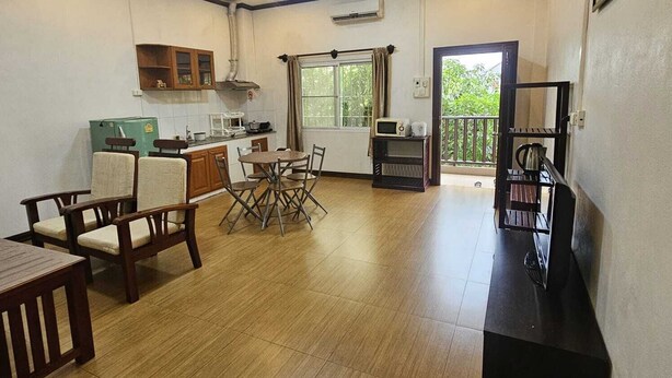A spacious kitchen with a dining area, wooden furniture, and a view of greenery outside. - ALI XAYATHIT APARTMENT & HOTEL (Vientiane)