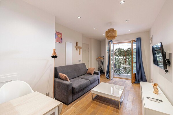 A modern living room with a grey sofa, a white coffee table, and a TV mounted on the wall.