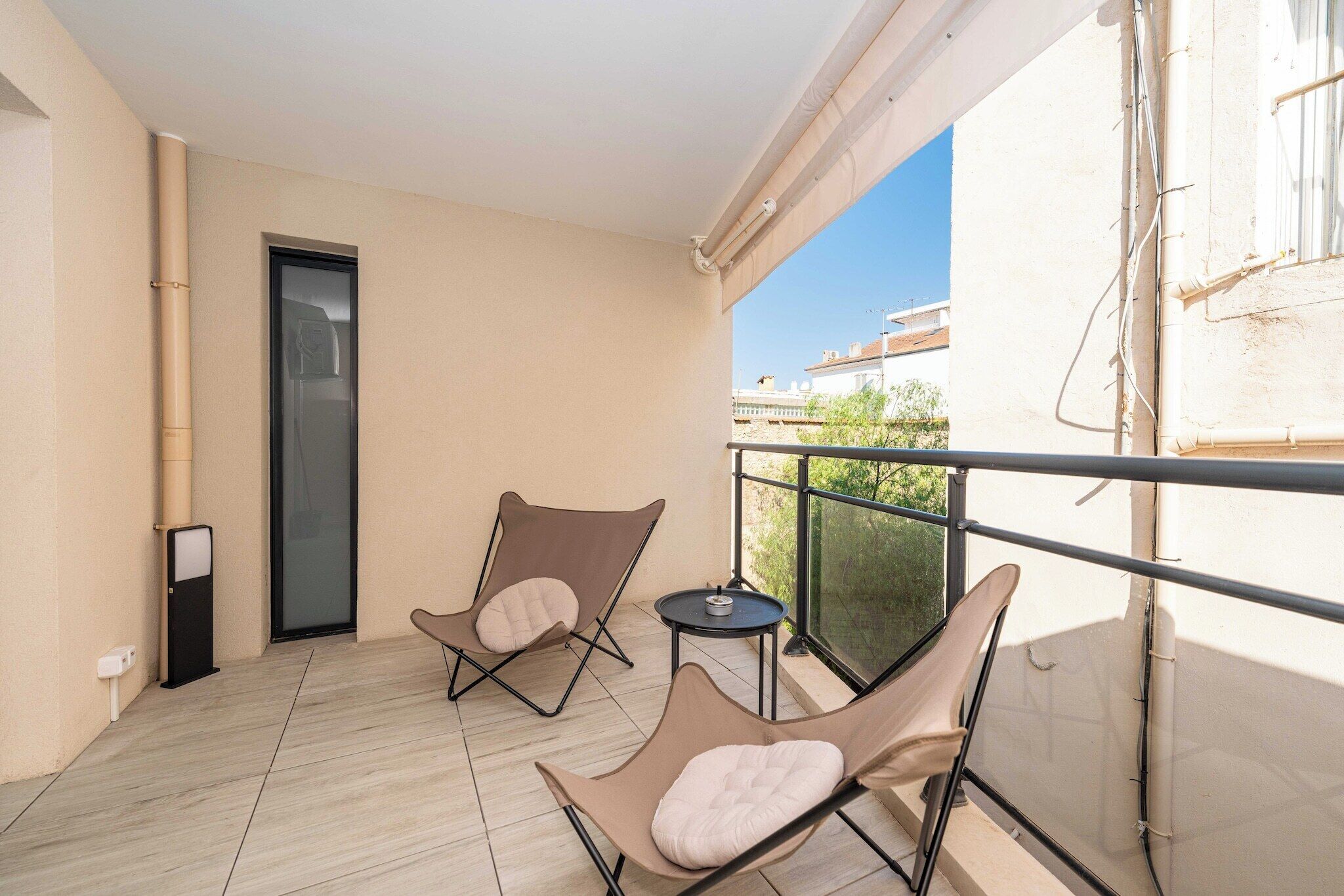 A balcony with two cushioned chairs, a small round table, and a door.