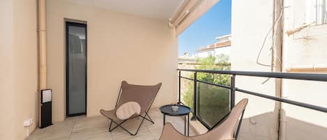 A balcony with two cushioned chairs, a small round table, and a door.