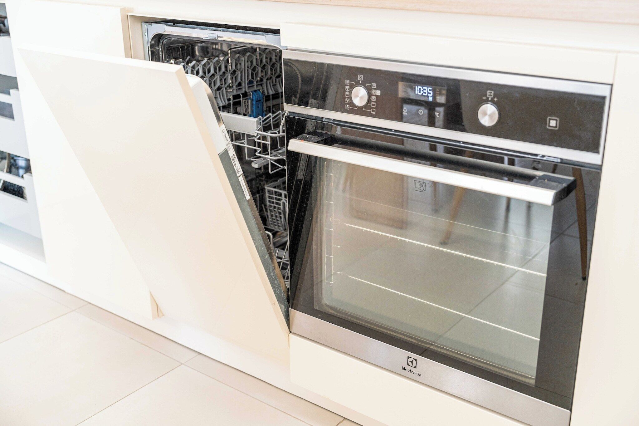 A modern kitchen with integrated dishwasher and oven, featuring stainless steel appliances and a clean, minimalist design.