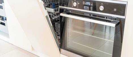 A modern kitchen with integrated dishwasher and oven, featuring stainless steel appliances and a clean, minimalist design.