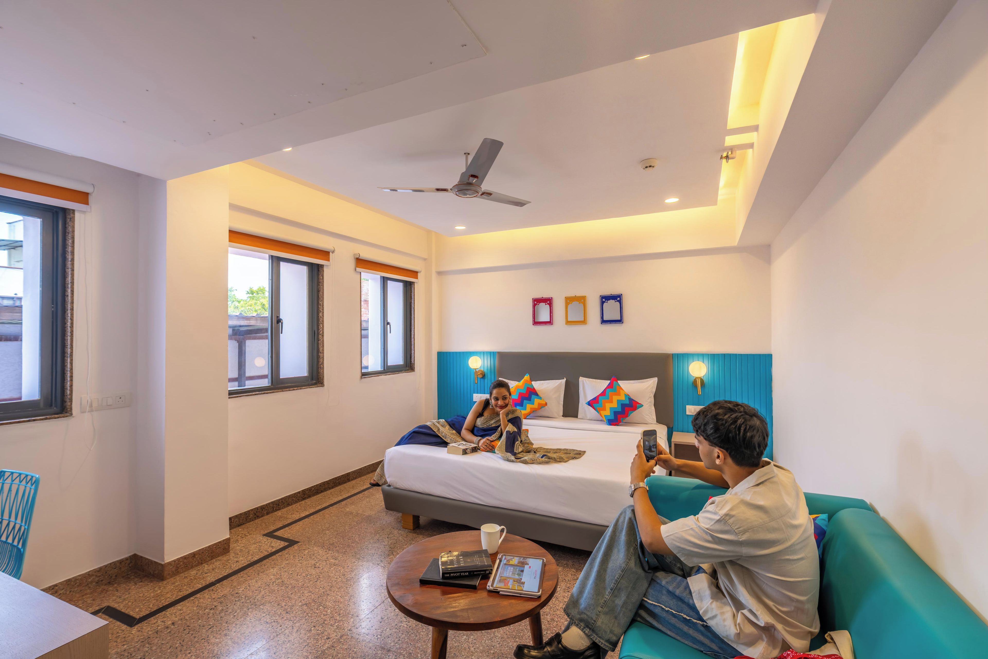 A hotel room with a bed, a ceiling fan, a coffee table, and a sofa.