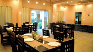 A restaurant with multiple tables and chairs, a no drinking sign, and a view of greenery outside. - Kudrat Resort : Jim Corbett (Chauk Patelia)