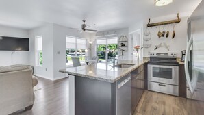 A modern kitchen with a central island, stainless steel appliances, and a dining area with a sofa.
