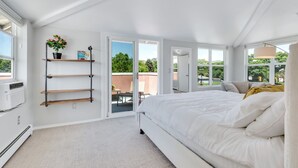 A modern bedroom with a large bed, built-in shelves, and a view of the outdoors.