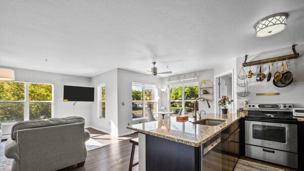 A modern kitchen with a central island, stainless steel appliances, and a dining area with a grey sofa.