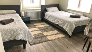 A bedroom with two beds, a small bedside table, a chair, and a radiator. - Apartment in Pellingen near Saar-Hunsrück (Pellingen)