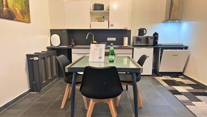 A compact kitchen with modern appliances, a dining table with chairs, and a small refrigerator.