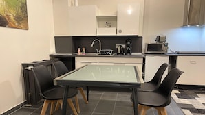 A compact kitchen with a glass-top table, black chairs, and a microwave.