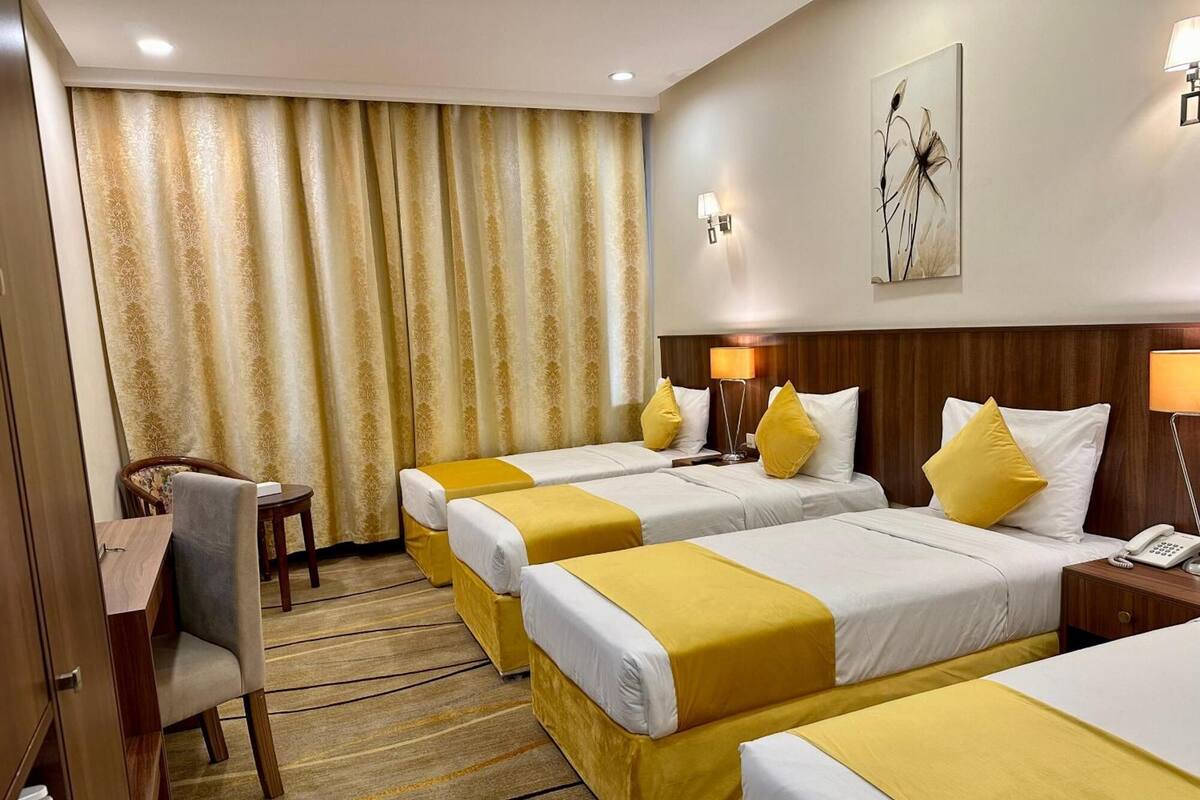 A hotel room with three beds, a desk, and a chair.