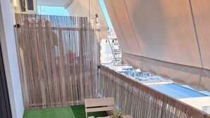 Un balcón con césped artificial, una mesa, sillas y una planta en maceta.