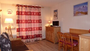 Une pièce confortable avec un bureau en bois, deux chaises, un lit, une télévision et un tableau accroché au mur.
