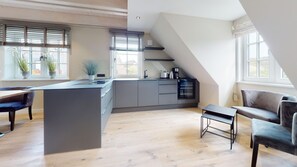 A modern kitchen with a central island, grey cabinets, and a dining area with a bench.