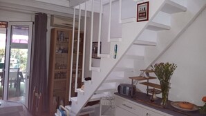 A staircase with white railings, a wooden cabinet with glassware, and a vase with flowers on the landing. - Corse, San giuliano, 50 kms de Bastia, maison à 2mn de la mer, animaux acceptés (san giuliano)