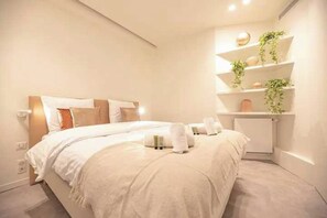 A modern hotel room with a large bed, a bedside table, and a built-in shelf with plants. - Superb Appt with AC - 2BD/6P - Madeleine/Opera (Paris)