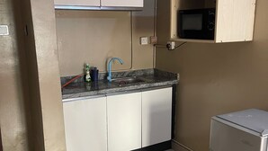 A compact kitchen with white cabinets, a granite countertop, a built-in microwave, and a small refrigerator. - Tranquil 1BR w/ Pool Access in Prime Ikeja GRA (Ikeja)