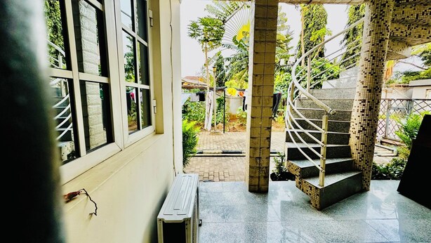 A staircase leading to a balcony with a view of a garden and a building in the background. - Tranquil 1BR w/ Pool Access in Prime Ikeja GRA (Ikeja)
