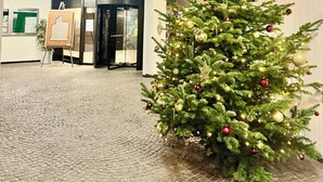 A lobby with a Christmas tree decorated with ornaments, a patterned ceiling, and a reception desk with a cityscape poster. - City Center Retreat/ 1 min Train Station (Köln)