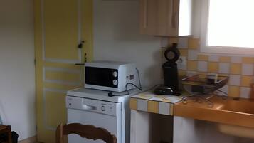 Una cucina compatta con forno a microonde, un piccolo forno, un lavandino e una sedia.